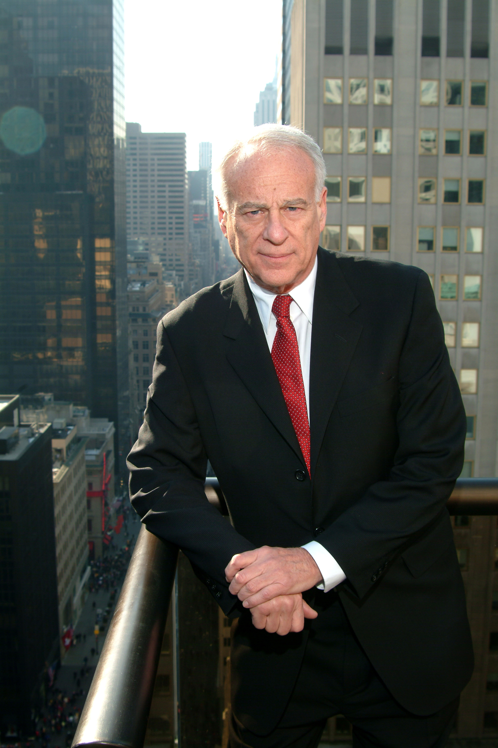 Portrait of Malcolm Bricklin (co-founder, Subaru of America; later Bricklin SV-1, Yugo/Global Motors, Visionary Vehicles), older, dark business suit, Manhattan balcony