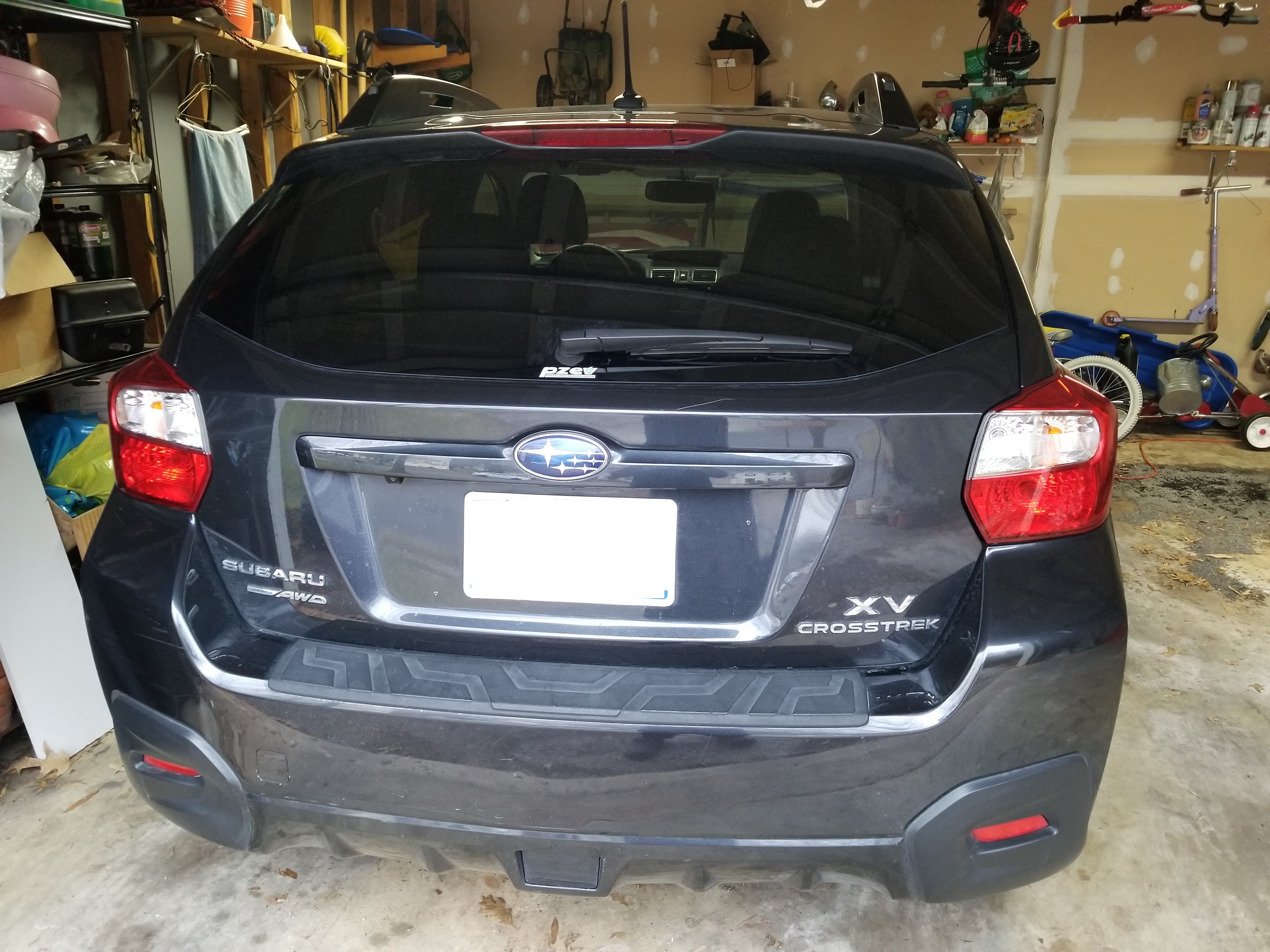 First-gen "XV Crosstrek" (US/Canada transitional naming, 2013-2015), black, rear view showing "XV / CROSSTREK" badging, home garage